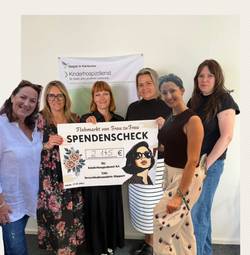 Eine Gruppe von Frauen hält einen großen Spendenscheck für den Kinderhospizdienst