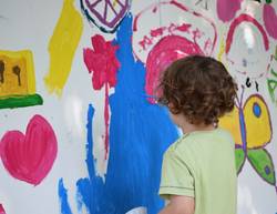 Junge malt mit Farben an die Wand